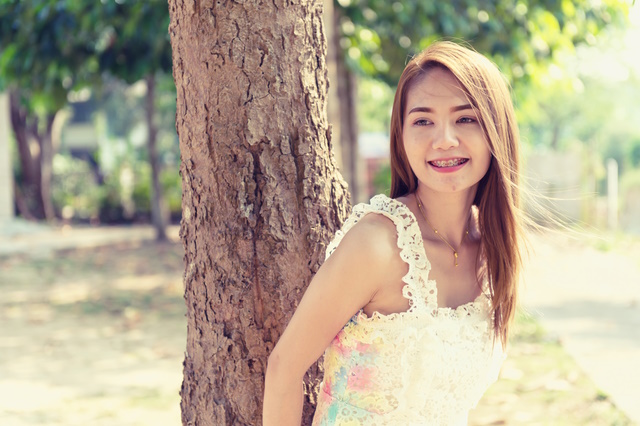 portrait of asia beautiful woman standing lying tree in park on sun