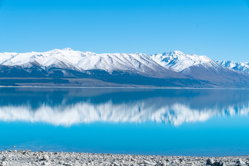 Snow capped mountains reflected in tranquil scenic Lake Pukaki in Mackenzie Basin Canterbury,NZ