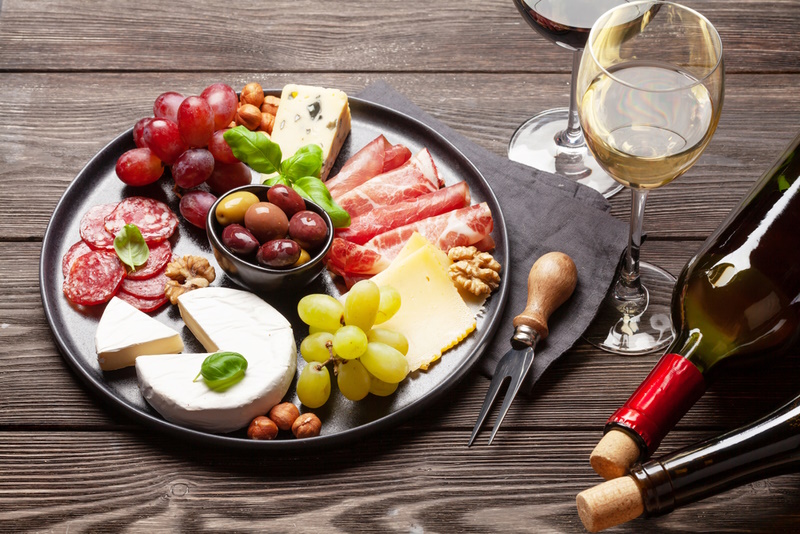 Cheese, meat, grapes and olives antipasto. Appetizer selection plate and glasses with red and white wine