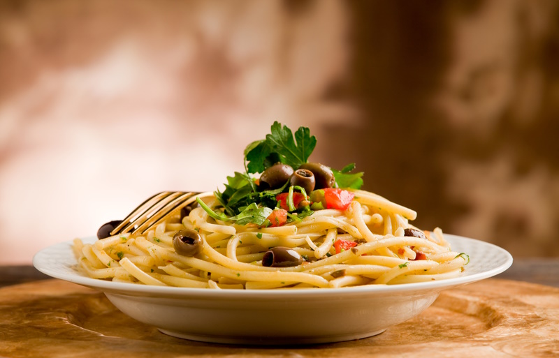 delicious vegetarian dish of pasta with olives and parsles on wooden table