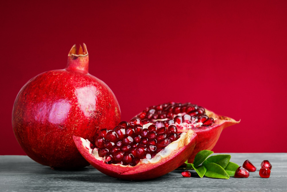 The Best Sony Macro Lens - Top Picks = Juicy pomegranate fruit with leaves on a red background