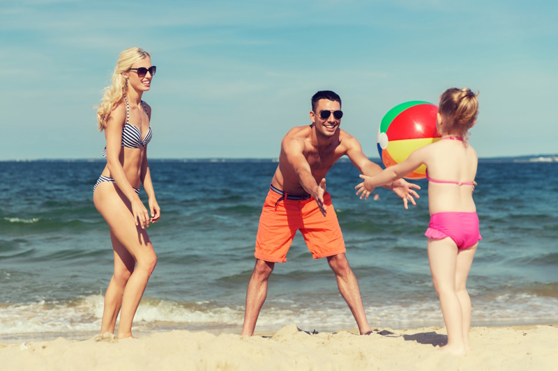 Beach Photography Ideas - family, summer vacation, adoption and people concept - close up of happy man, woman and little girl playing with inflatable ball on beach