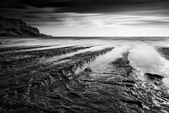Stunning black and white seascape coastline and rocky shore at sunset