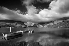 Black and white View of rowing boats on Llyn Nantlle in Snowdonia landscape at sunset