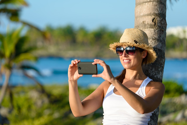 Mobile photography tutorial- Woman on caribbean tropical vacation taking photos with smartphone camera. Brunette tourist on travel to Riviera Maya, Mexico.